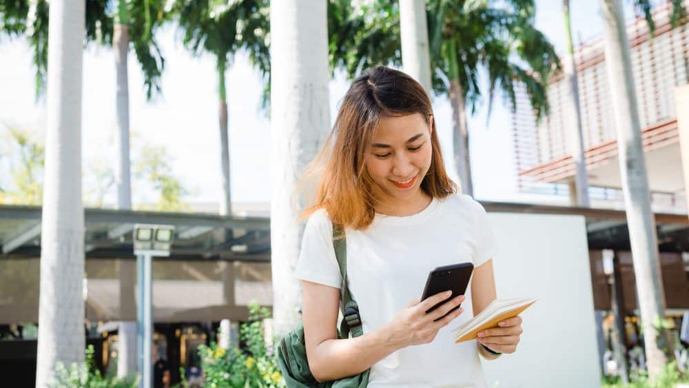 asian woman tourist backpacker using smartphone traveling alone