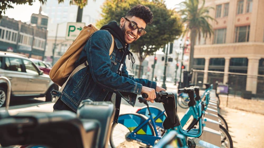 stylish young man on the street with rental bike