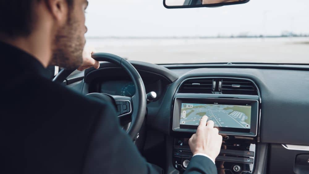 rear view of man using global positioning system device to check the map while driving a car