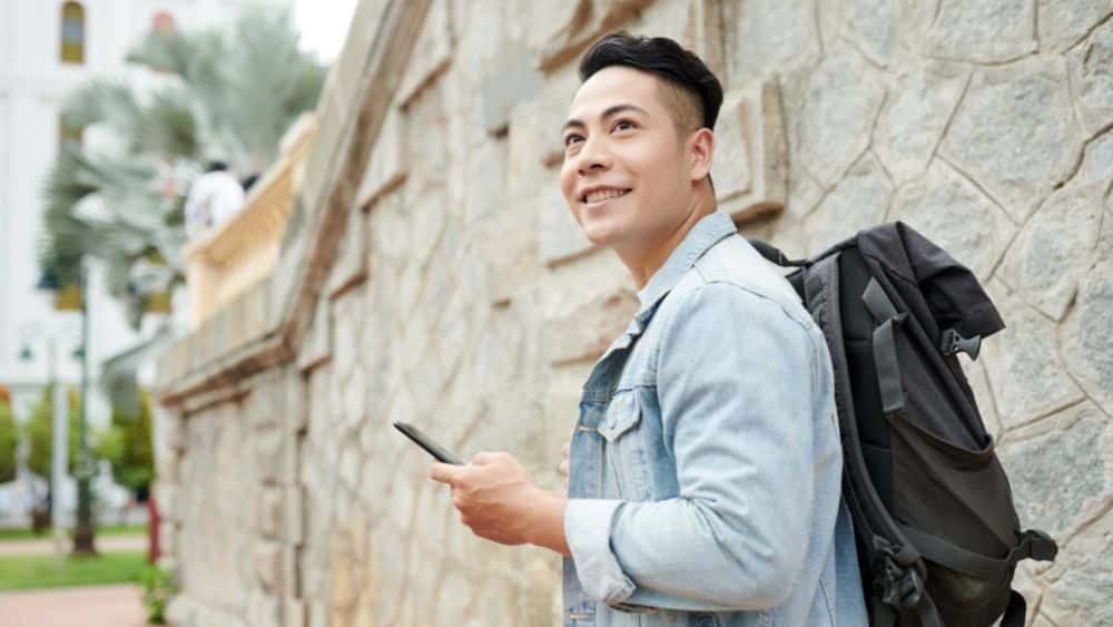 positive asian man traveling alone