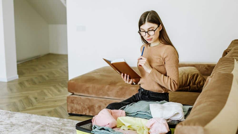 young woman makes checklist of things to pack for trip
