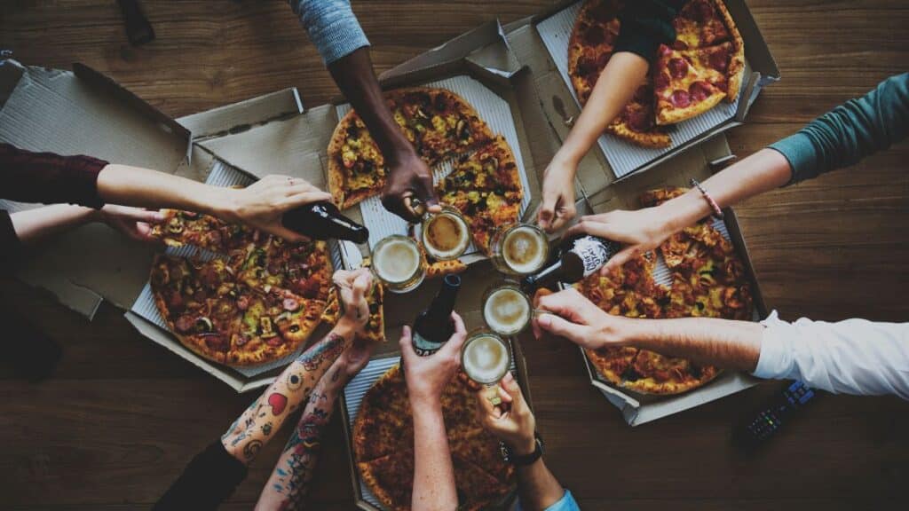 people having fun eating pizza drinking beers
