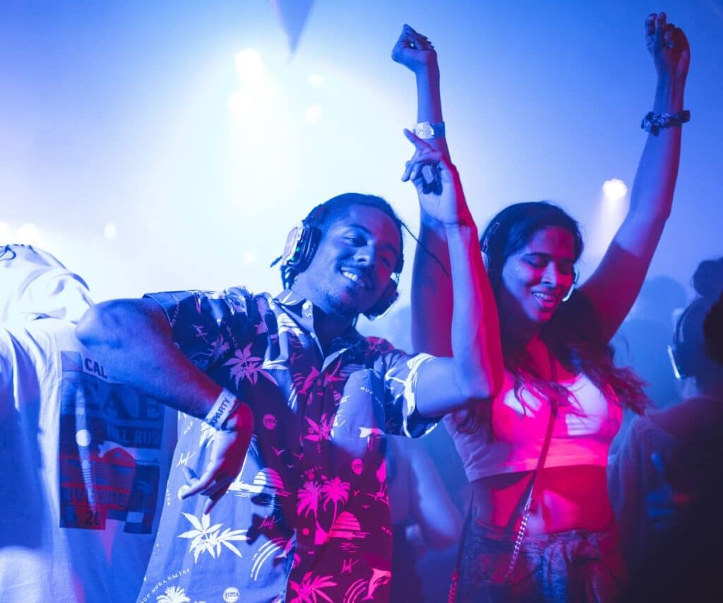 smiling man standing and dancing near smiling woman surrounded by people