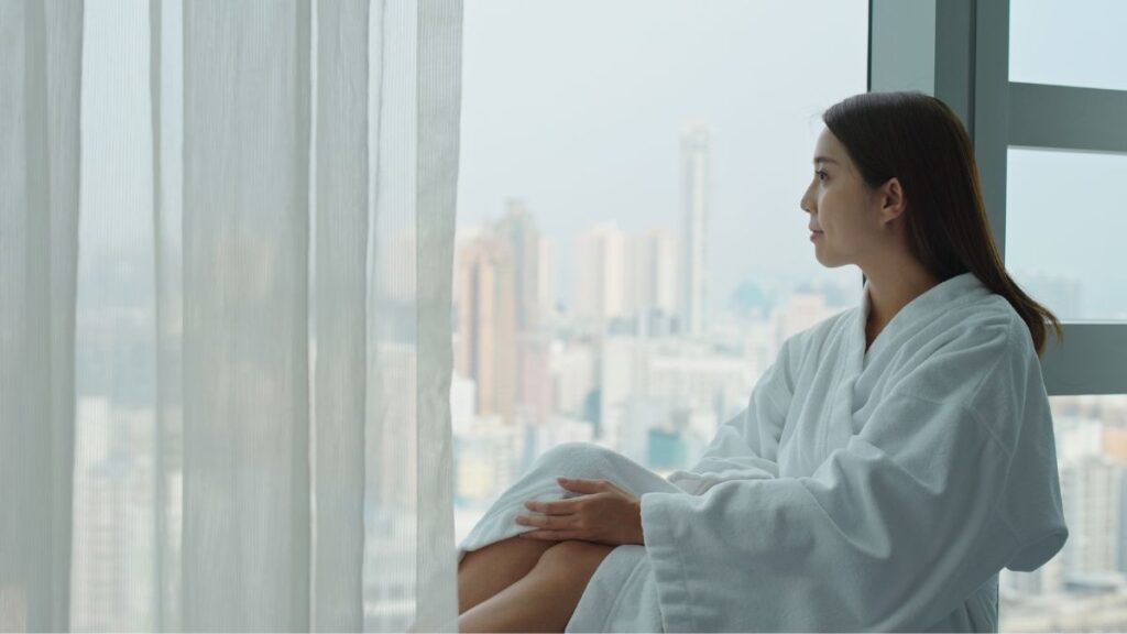 woman enjoying the city view at hotel room