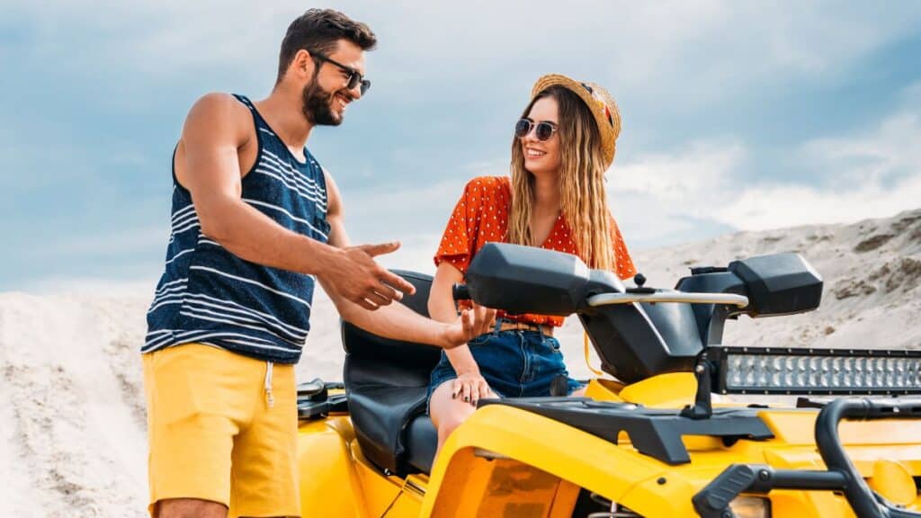 happy young man teaching his girlfriend how to ride an ATV