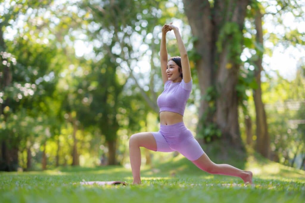 beautiful asian woman practicing yoga poses in the park