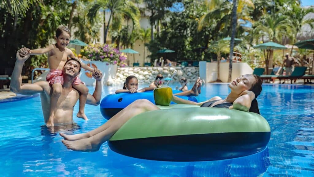 occidental at xcaret woman lounging in pool with her family in the background