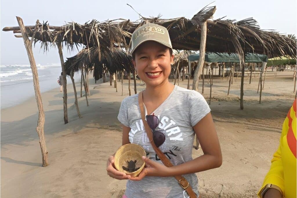 pretty woman holding a baby turtle at the beach