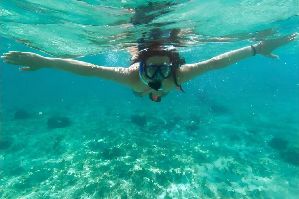 woman snorkeling in shallow waters just above a coral reef