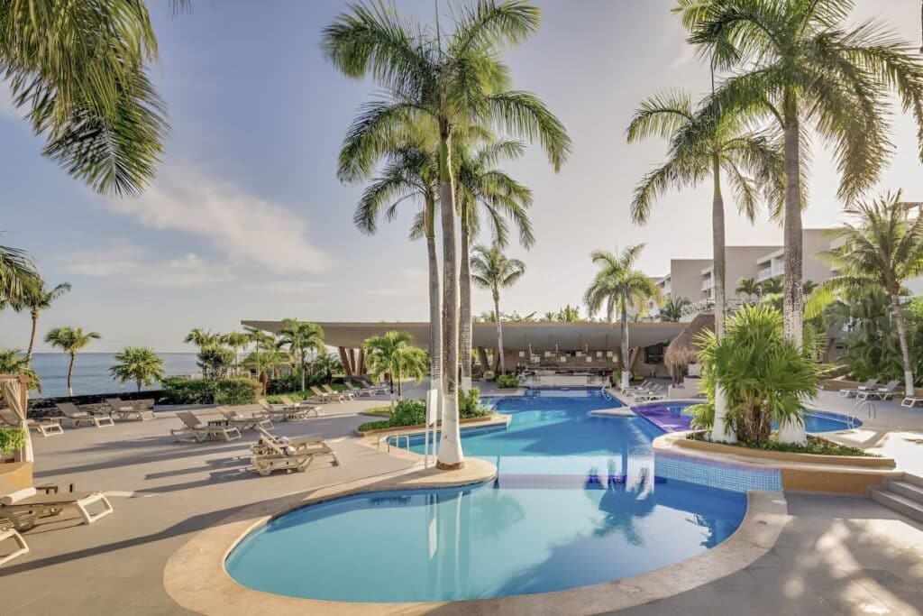 outdoor pool overlooking the beach with cabanas and palm trees