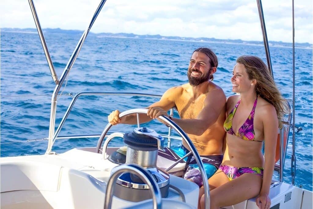 attractive couple at the helm of a luxury catamaran