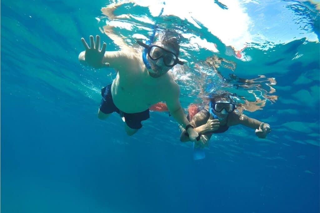 couple scuba diving waving and giving thumbs up