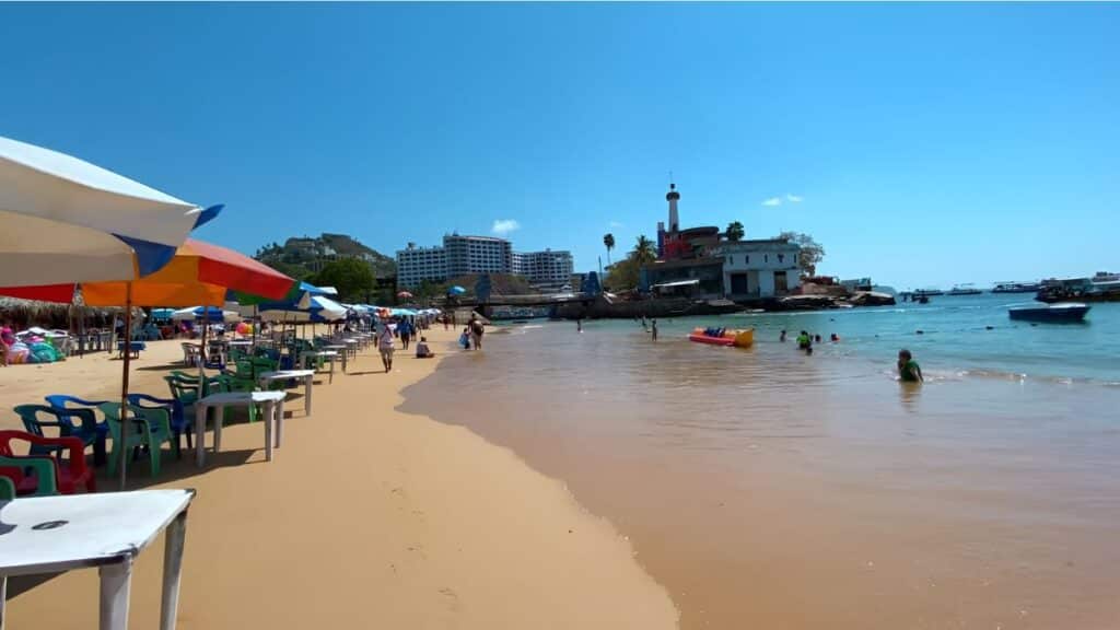 people enjoying themselves at playa caletilla on a sunny day