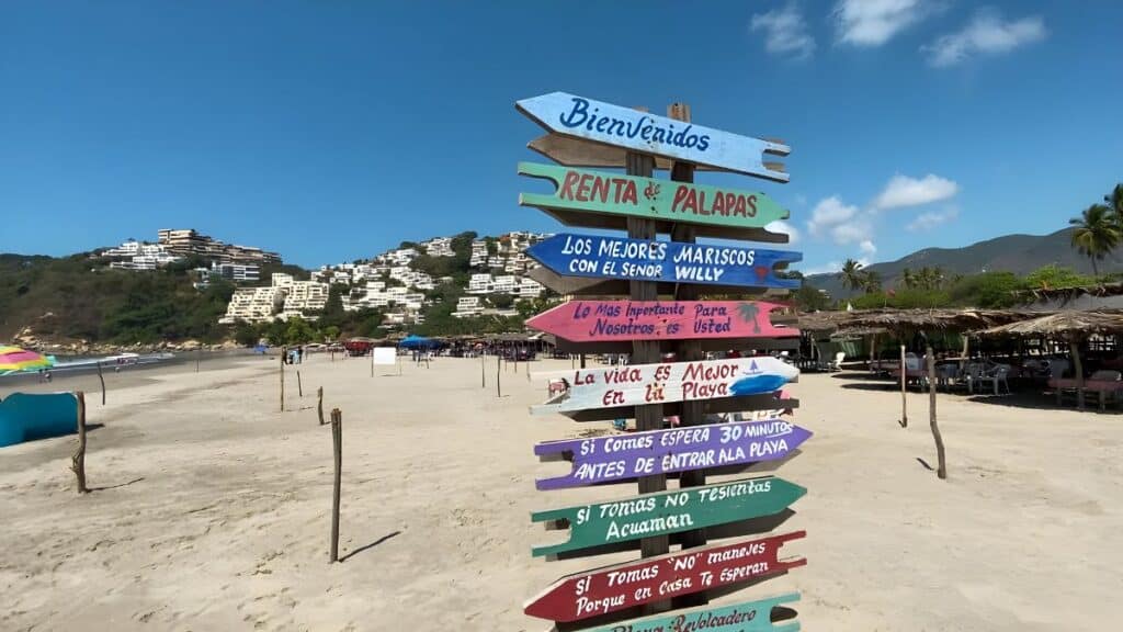 colorful spanish signs at playa revolcadero with mountains in the background