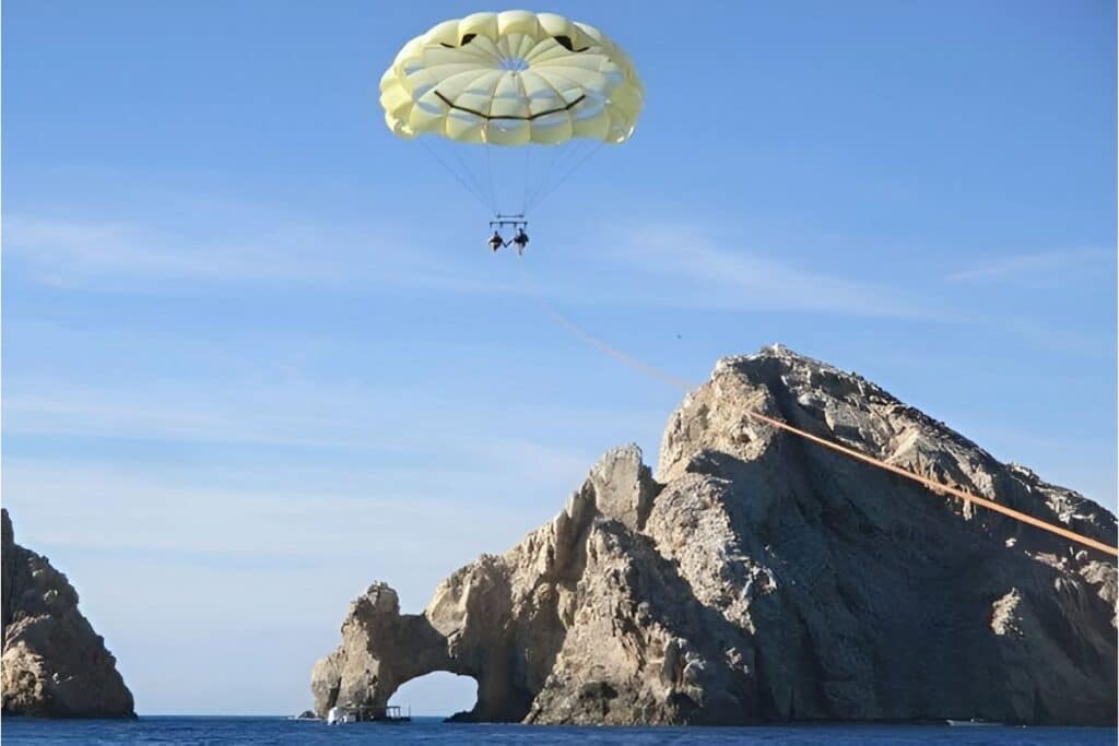 photo taken from the boat of two people parasailing with a happy face parachute